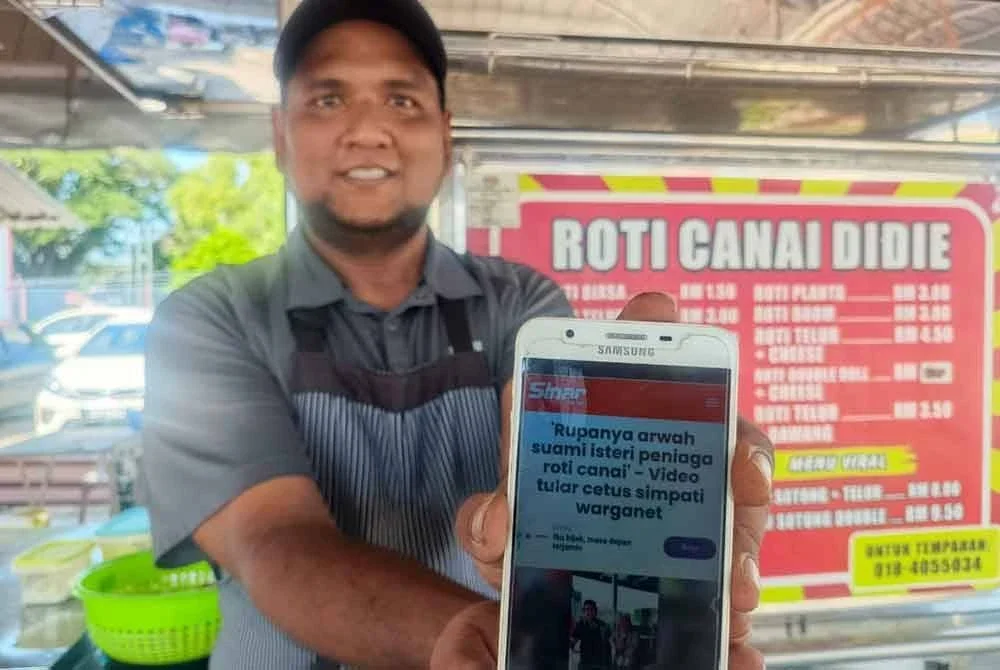 Mohd Najmuddin menunjukkan laporan Sinar Harian berkenaan video pasangan tersebut yang berniaga roti canai dan tular sebelum ini.