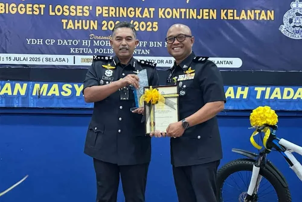 Mohd Ali (kiri) menyampaikan Anugerah Ibu Pejabat Polis Terbaik bagi Program Biggest Losses kepada Ketua Polis Daerah Pasir Puteh, Superintendan Zaizul Rizal Zakaria (kanan).