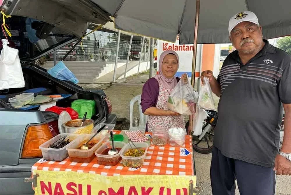 Saad (kanan) dan Siti Halijah (kiri) menunjukkan nasi lemak yang dijual di gerai di tepi jalan di Pengkalan Chepa, Kota Bharu.