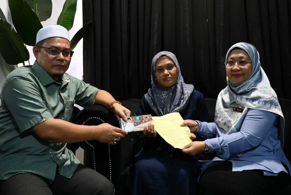 Suhara (kanan) dan Hishamuddin (dua dari kiri) menyerahkan manfaat perlindungan di bawah PERKESO kepada Rusmailaili di kediamannya di Taman Batin Perdana, Kuala Nerus.