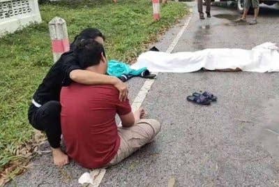 Seorang ahli keluarga cuba menenangkan Nawi yang menangis di sisi jasad ibunya. Foto Agensi