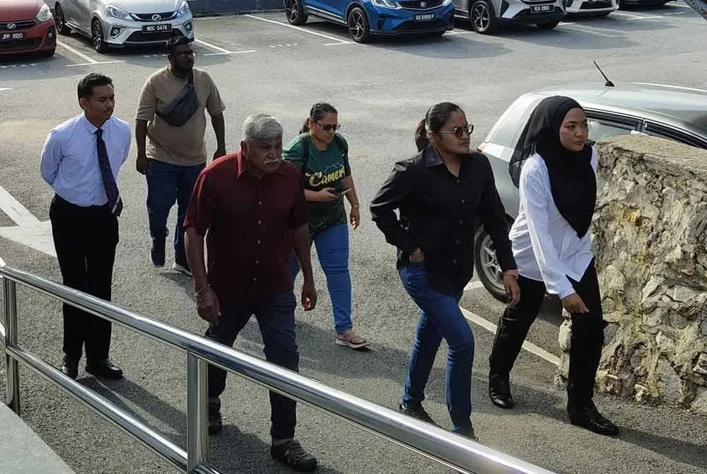 Tertuduh (dua dari kanan) tiba di Mahkamah Kuala Pilah pada Khamis.