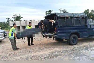Anggota polis mengangkat mayat mangsa yang ditemui dengan kesan kelartapak pembinaan perumahan di Taman Madani, Bandar Al Muktafi Billah Shah (AMBS) di Dungun pada petang Khamis. 
