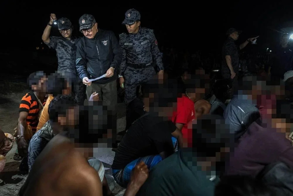 James (tengah) memeriksa dokumen warga asing ketika menyertai operasi bersepadu JIM Perak dan Pasukan Gerakan Am (PGA) di sebuah tapak pembinaan di Persiaran Panorama Lapangan Perdana awal pagi Sabtu. Foto Bernama 