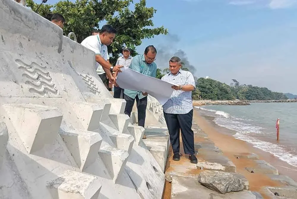 Rais (kanan) melihat pelan projek naik taraf benteng pantai ketika lawatanya di kawasan tapak projek.