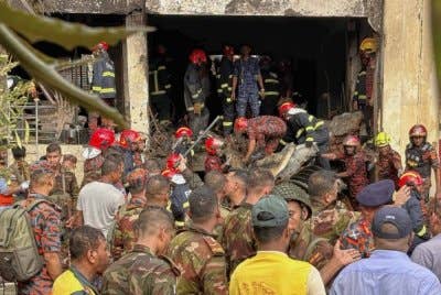 Anggota bomba memeriksa serpihan pesawat latihan milik Tentera Udara Bangladesh yang terhempas di kawasan sekolah di Dhaka, Bangladesh, pada Isnin.