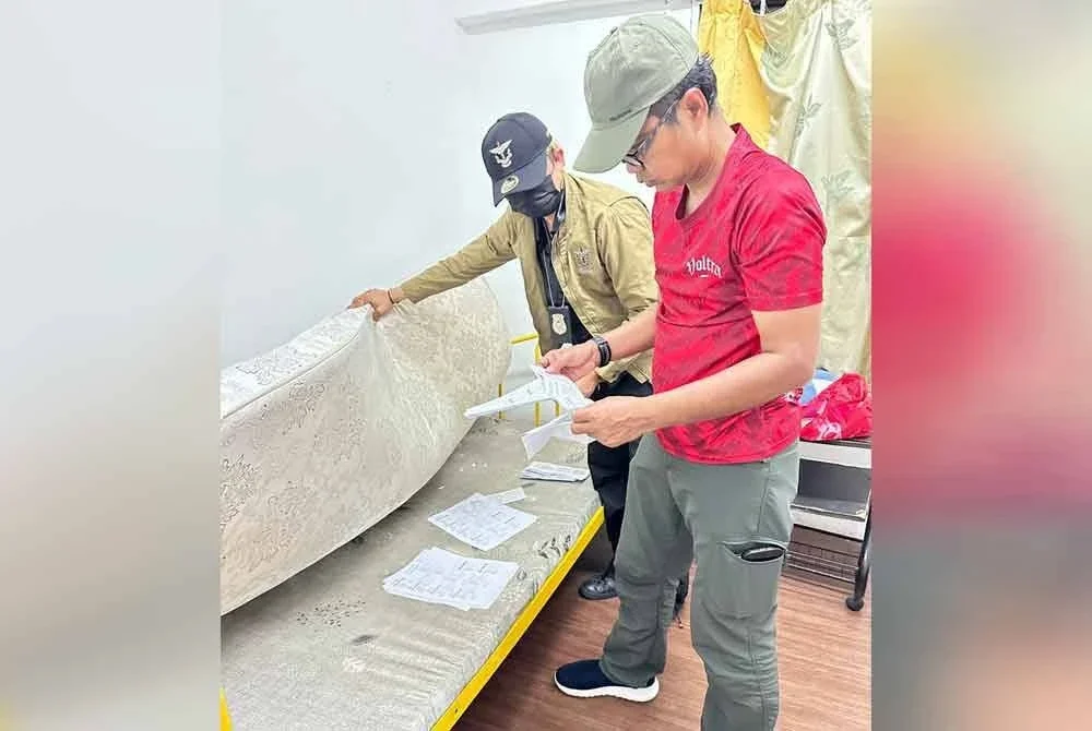 Wan Mohammed Saupee (kanan) meneliti antara dokumen yang ditemui dalam serbuan di sebuah unit apartment di Kepong pada Isnin.