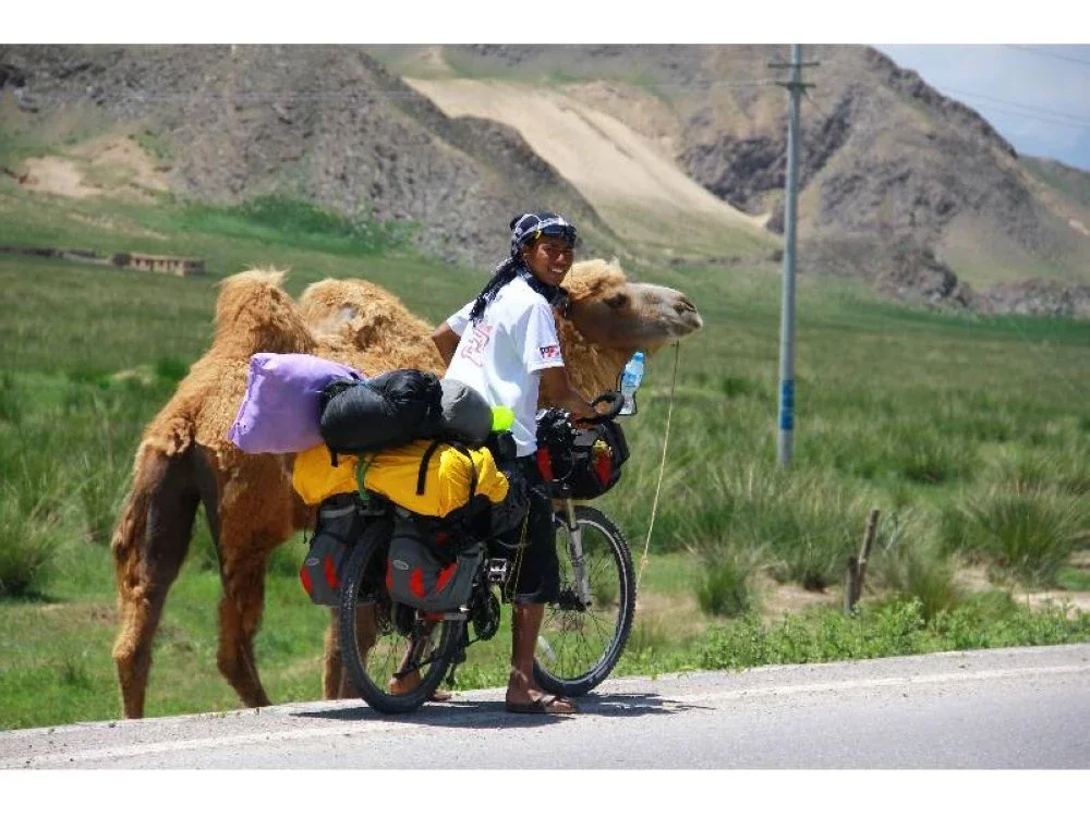 Zahariz bergambar dengan seekor unta ketika mengayuh basikal dalam perjalanan di Gurun Taklamakan yang terletak di Xinjiang Selatan, China.
