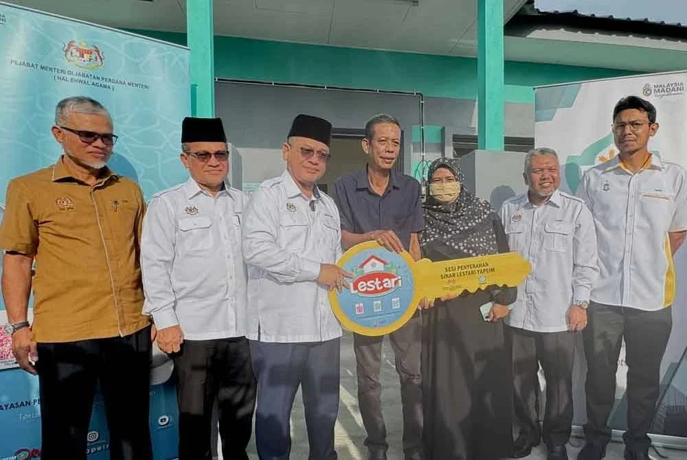 Mohd Na'im (tiga dari kiri) menyerahkan replika kunci kepada Tahir dan isterinya pada Program Sinar Lestari YAPEIM di Penaga pada Rabu.