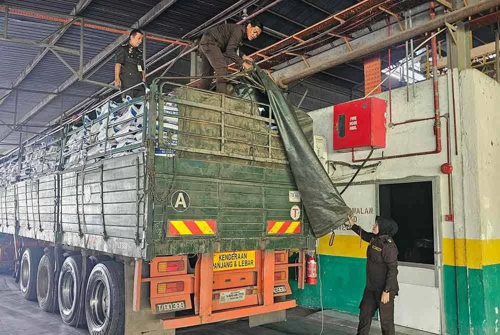 Nurul Zhahirah (kanan) menunjukkan treler yang berjaya ditahan berikutan membawa muatan guni beras dipercayai diseludup dari Thailand sebelum ditahan di Gerik pada Selasa.