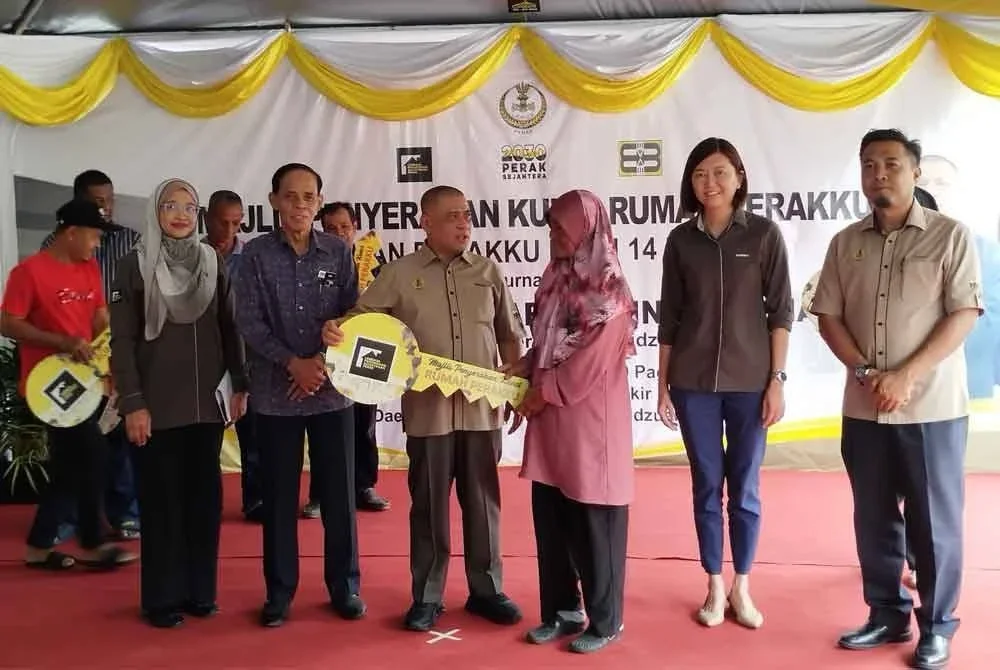 Saarani (tiga dari kiri) menyerahkan replika kunci kepada penerima ketika Majlis Penyerahan Kunci Rumah Perakku di Taman Perakku Batu 14, Lekir pada Khamis.