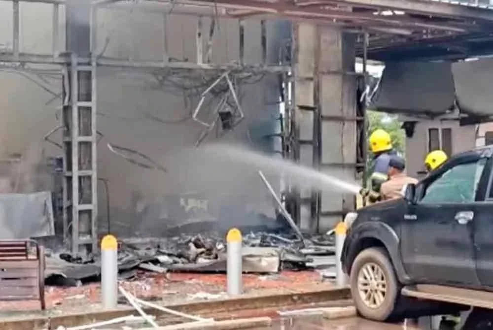 Anggota bomba mengawal kebakaran di sebuah premis perniagaan yang menjadi sasaran bedilan Kemboja. Foto Agensi