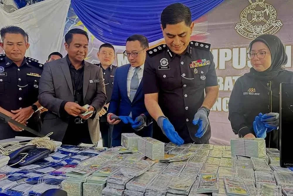 Ku Mashariman (dua dari kanan) menunjukkan mata wang Amerika Syarikat palsu yang dilupuskan pada Jumaat.