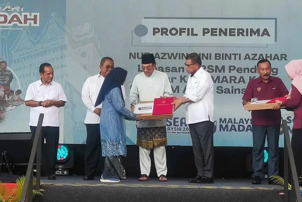 Anwar menyampaikan sumbangan komputer riba kepada seorang pelajar pada Program Sambutan Hari Antidadah 2025 di Jitra pada Jumaat.