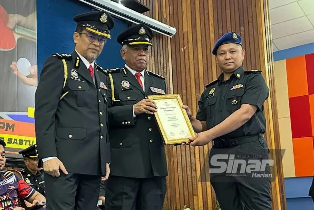 Aris (tengah) diiringi Azman (kiri) menyampaikan anugerah cemerlang kepada anggota KPDN di Kelantan.