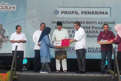 Anwar menyampaikan sumbangan komputer riba kepada seorang pelajar pada Program Sambutan Hari Antidadah 2025 di Jitra pada Jumaat.