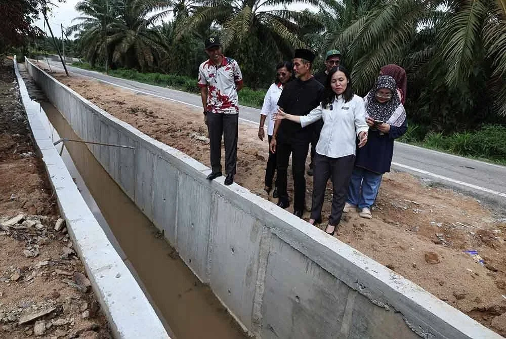 Nie Ching (kanan) melihat longkang konkrit yang telah disiapkan bagi menangani masalah banjir di Kampung Melayu Bukit Batu, Kulai pada Sabtu.
