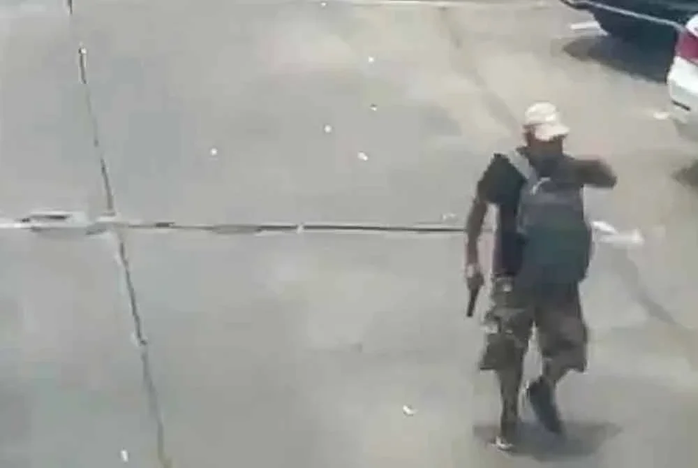 Seorang lelaki bersenjata dilihat berjalan di kawasan berhampiran Pasar Or Tor Kor, Bangkok, tempat insiden tembakan rambang yang mengorbankan enam nyawa pada Isnin. – Agensi