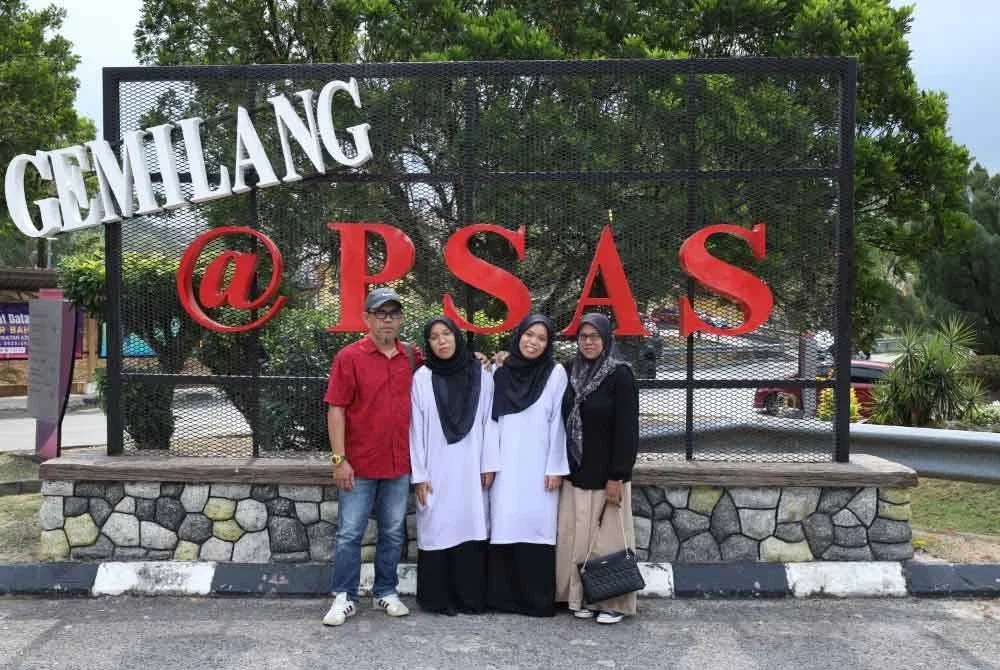 Pasangan kembar Nur Ain Nabila (kiri) dan Nur Ain Nafisa (kanan) bersama ibu serta bapa ketika mendaftar masuk ke PSAS, Behrang pada Ahad.