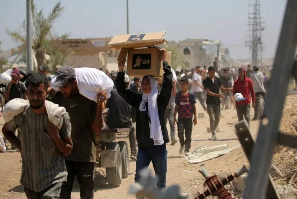 Penduduk Palestin membawa pulang bekalan makanan yang diagihkan kepada mereka. Foto AFP