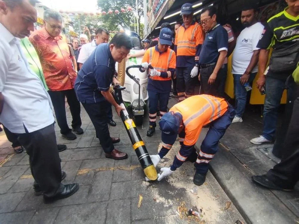 Pengerusi SWCorp, Hee Loy Sian (tengah) mencuba sendiri mesin pembersih jalan berkenaan.