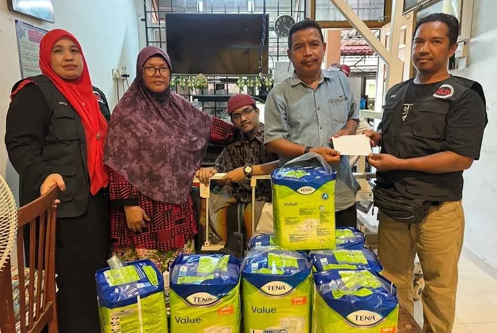 Mohd Izahir (dua dari kanan) menerima sumbangan bagi pihak Muhammad Faiz Hafizuddin yang disampaikan Rusmawi (kanan) di Taman Sri Sentosa, Bukit Bidang, Pasir Puteh pada Isnin.