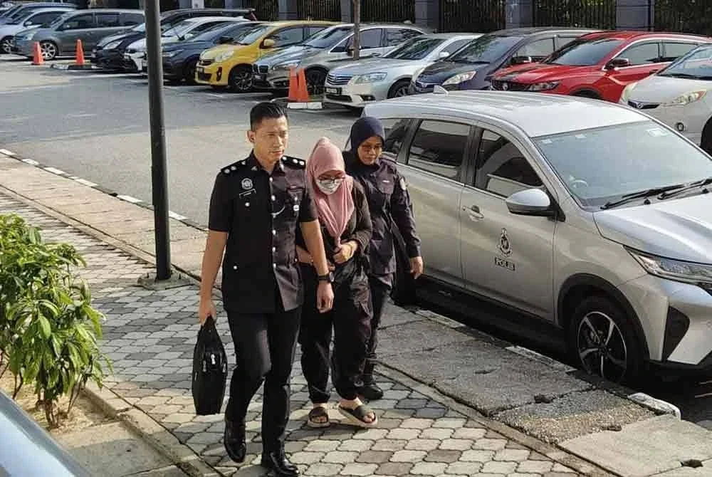 Tertuduh (tengah) tiba di Mahkamah Sesyen Seremban pada Selasa.