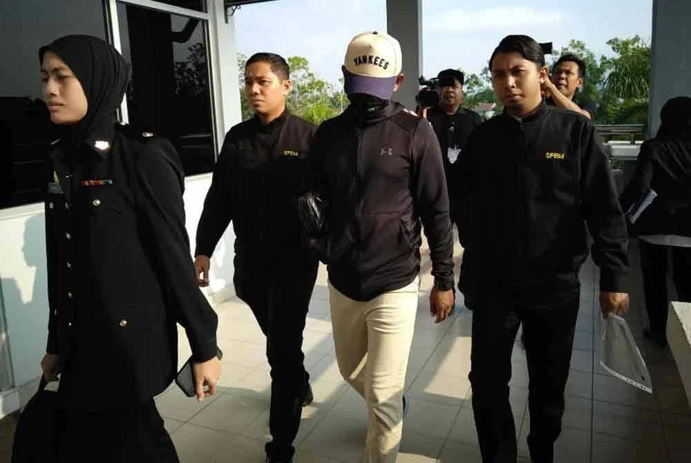 Tertuduh (dua dari kanan) tiba di Mahkamah Sesyen Seremban pada Selasa.