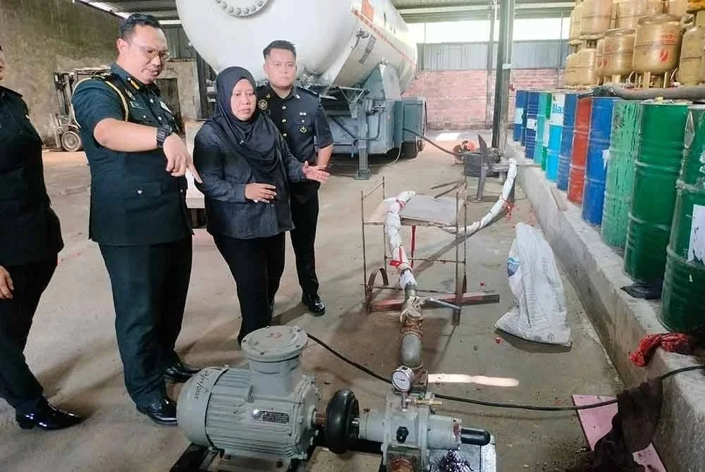 Lilis Saslinda (dua dari kanan) melihat peralatan yang digunakan sindiket pemindahan gas LPG bersubsidi di Ulu Tiram.