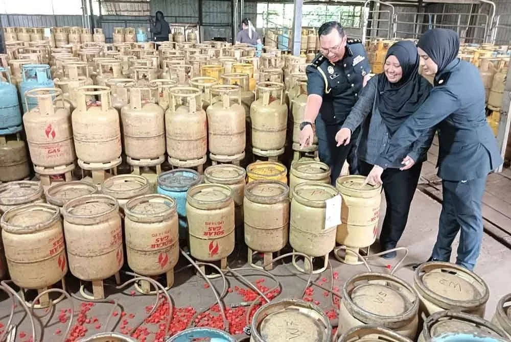 Lilis Saslinda (tengah) melihat tong gas LPG bersubsidi yang disorok di sebuah stor haram di Ulu Tiram.