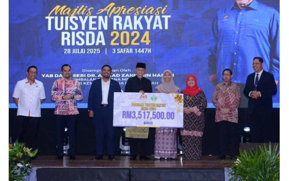 Ahmad Zahid (tengah) menyampaikan cek cura berjumlah RM3,517,500.00 kepada wakil penerima pada Majlis Apresiasi Tuisyen Rakyat RISDA 2024 di sini pada Isnin.