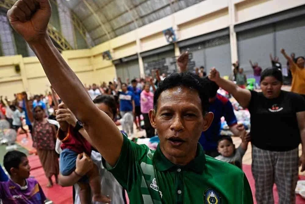 Mangsa yang dipindahkan menyanyikan lagu kebangsaan Thailand di pusat pemindahan di Surin susulan gencatan senjata tanpa syarat antara Thailand dan Kemboja. - AFP