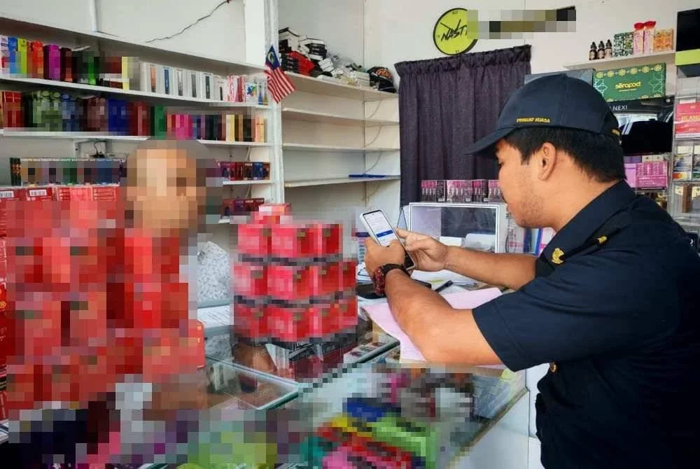 Anggota penguat kuasa KPDN Terengganu memeriksa cecair isian semula rokok elektronik disyaki tiruan yang dirampas dalam operasi bersepadu di sekitar Kuala Terengganu dan Kuala Nerus, pada Selasa.