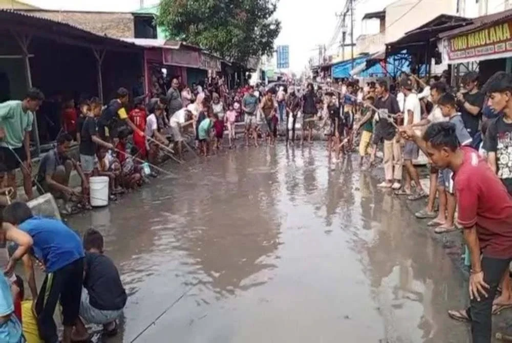 Penduduk memancing di lopak jalan rosak di Jalan Setia Makmur, Sunggal, Sumatera Utara, Indonesia. Foto Agensi