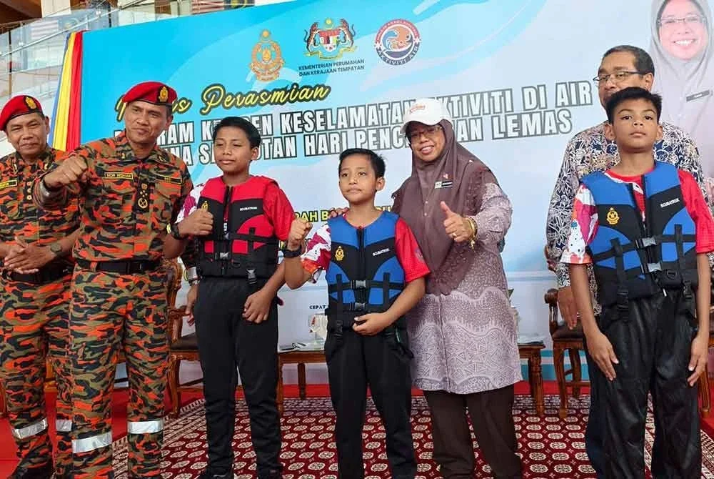 Nor Hisham (dua dari kiri) Dan Aiman Athirah (tengah) memakaikan jaket keselamatan Program Kempen Keselamatan Aktiviti di Air Sempena Hari Pencegahan Lemas Sedunia