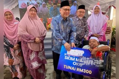 Mohd Amar (tengah) menyampaikan sumbangan kepad penerima pada Karnival Kelantanku Cakna di Masjid Jamek Muhammadi, Kota Bharu pada Khamis. Foto Sinar Harian HAZELEN LIANA KAMARUDIN