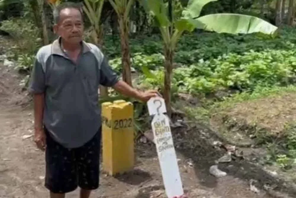 Wakil penduduk menunjukkan kubur lengkap dengan batu nisan di tepi jalan yang turut jadi tular di media sosial. - Foto Agensi