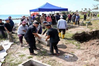Waris dan ahli keluarga yang dipantau oleh pegawai Pejabat Agama Daerah Kuala Nerus mengangkat kepok kubur bagi proses dokumentasi jenazah selepas kubur digali semula untuk dipindahkan ke kawasan perkuburan lain semasa tinjauan di Tanah Perkuburan Islam Kampung Pengkalan Maras pada Sabtu. Foto Bernama