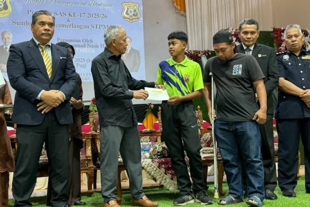 Mohd Salmimi (tiga dari kanan) mengiringi anaknya, Muhammad Shahir (empat dari kanan) menerima bantuan SAS yang disampaikan oleh Muhammad Nasir (dua dari kiri) pada Majlis Penyerahan SAS kali ke-17 2025/26 dan Sumbangan Kecemerlangan Sijil Tinggi Persekolahan Malaysia (STPM) di SMK Tengku Mahmud, Besut pada Isnin.
