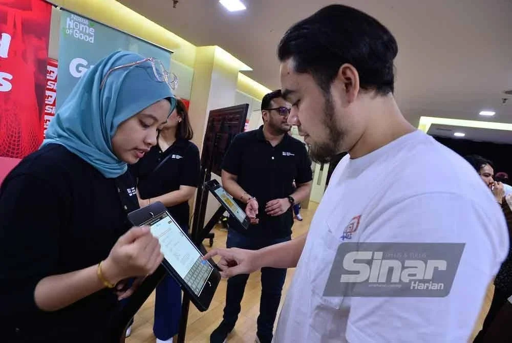 Kakitangan Nestlé memberi tunjuk ajar tentang kuiz interaktif disediakan semasa program. FOTO: ASRIL ASWANDI SHUKOR