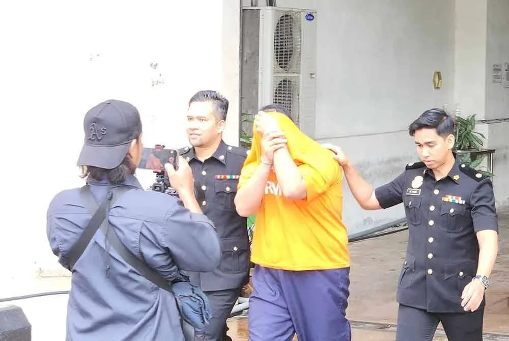 Suspek diiringi pegawai SPRM ketika dibawa ke mahkamah pada Selasa untuk perintah reman.