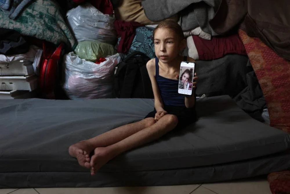 Rahaf Ayyad, kanak-kanak perempuan Palestin berusia 12 tahun yang mengalami kekurangan zat makanan, menunjukkan gambar lamanya ketika berada di sebuah sekolah yang dijadikan tempat perlindungan di al-Rimal, Gaza Tengah.