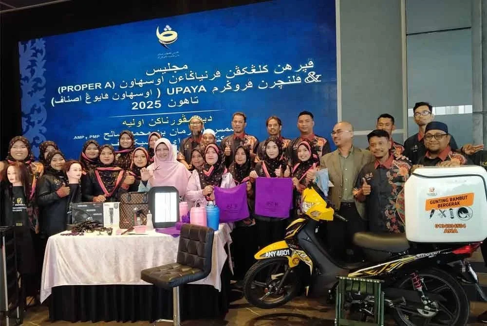 Syamsul Hazeman (tiga dari kanan) dan peserta yang menyertai projek gunting rambut bersama-sama peralatan termasuk motosikal ketika Majlis Penyerahan Kelengkapan Perniagaan Usahawan dan Pelancaran Program Upaya Tahun 2025 di Vetro Hall Galasa pada Selasa.