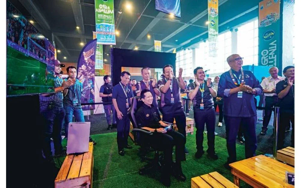 Arthur (duduk) mencuba permainan PS5 selepas merasmikan kejohanan e-sukan.