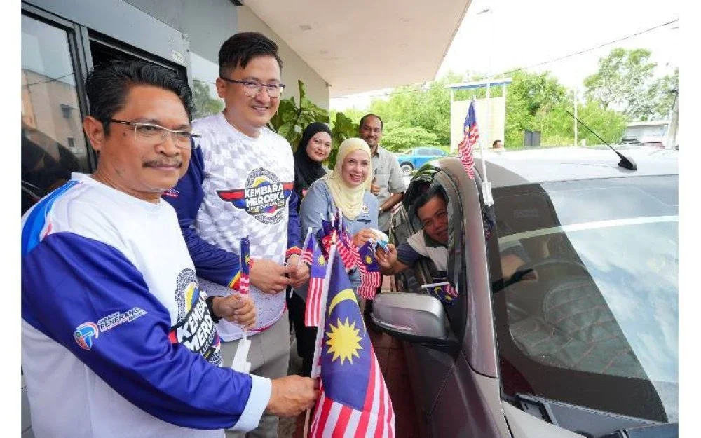 Melati menyerahkan Jalur Gemilang dan pelekat pandu lalu khas kepada salah seorang pelanggan pandu lalu di McDonald's Batu Berendam.