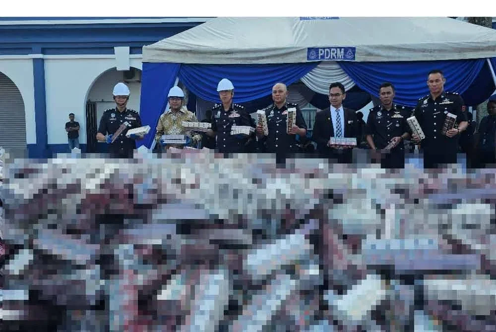 Luqman (kiri) bersama Mohamad Nasir (tiga dari kanan) menunjukkan lebih 10,000 karton rokok yang berjaya dirampas dan dilupuskan dalam Majlis Pelupusan Mega Barang Kes di IPD Taiping pada Khamis.