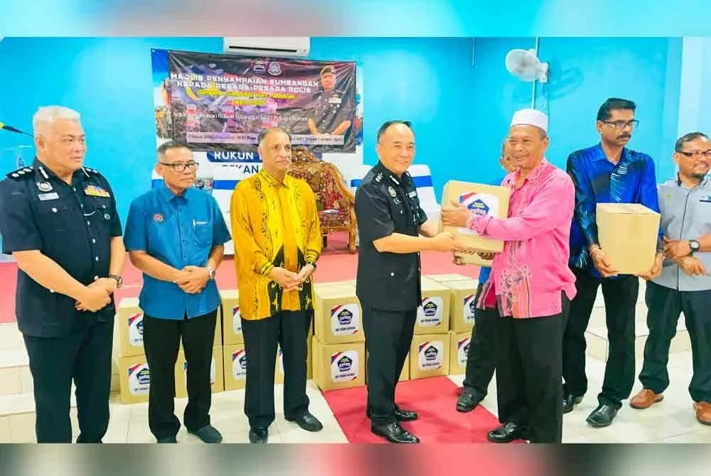 Zaihairul (empat dari kiri) diiringi Abang Zainal (kiri) menyampaikan kotak barangan asas kepada pesara polis Sempena Sambutan Hari Pahlawan 2025 di Dewan Perpaduan Kawasan Rukun Tetangga (KRT) Pekan Chemor pada Khamis.
