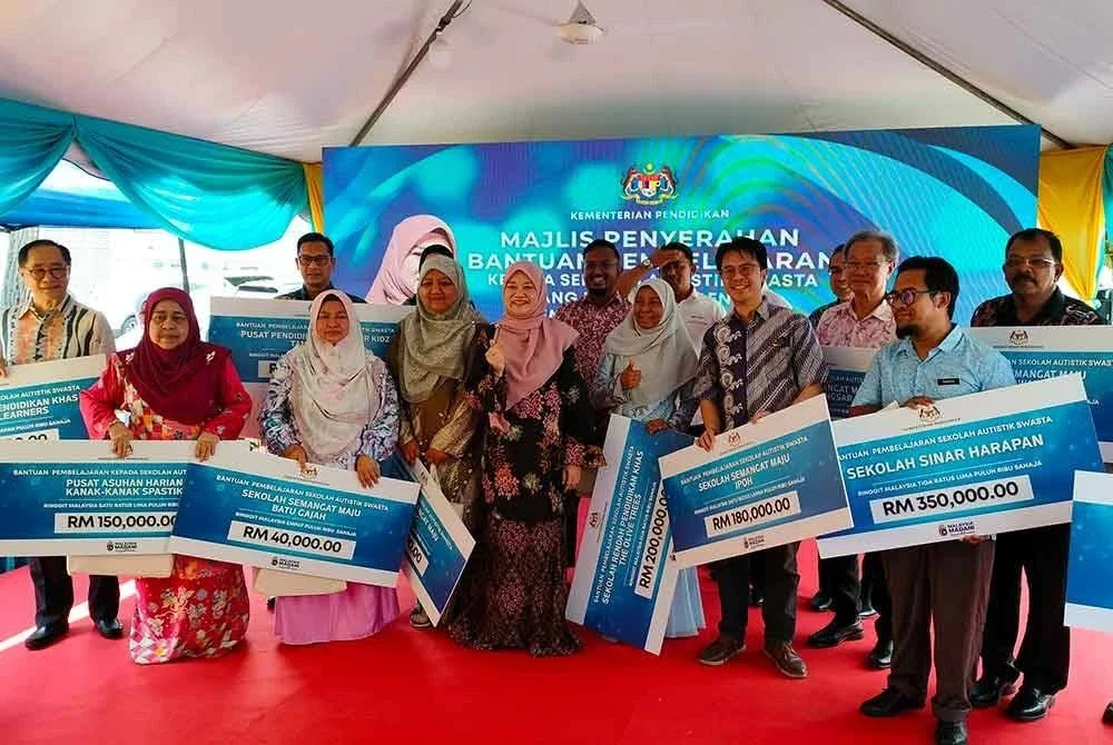 Fadhlina (tengah) bergambar bersama penerima Cek Cura Sekolah Autistik di Bukit Mertajam pada Khamis.