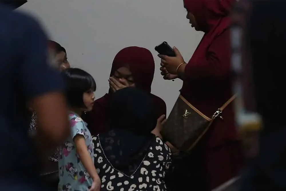 Nur Azhanis (tengah) ditenangkan oleh kenalannya di Jabatan Forensik Hospital Sultanah Bahiyah pada malam Khamis.
