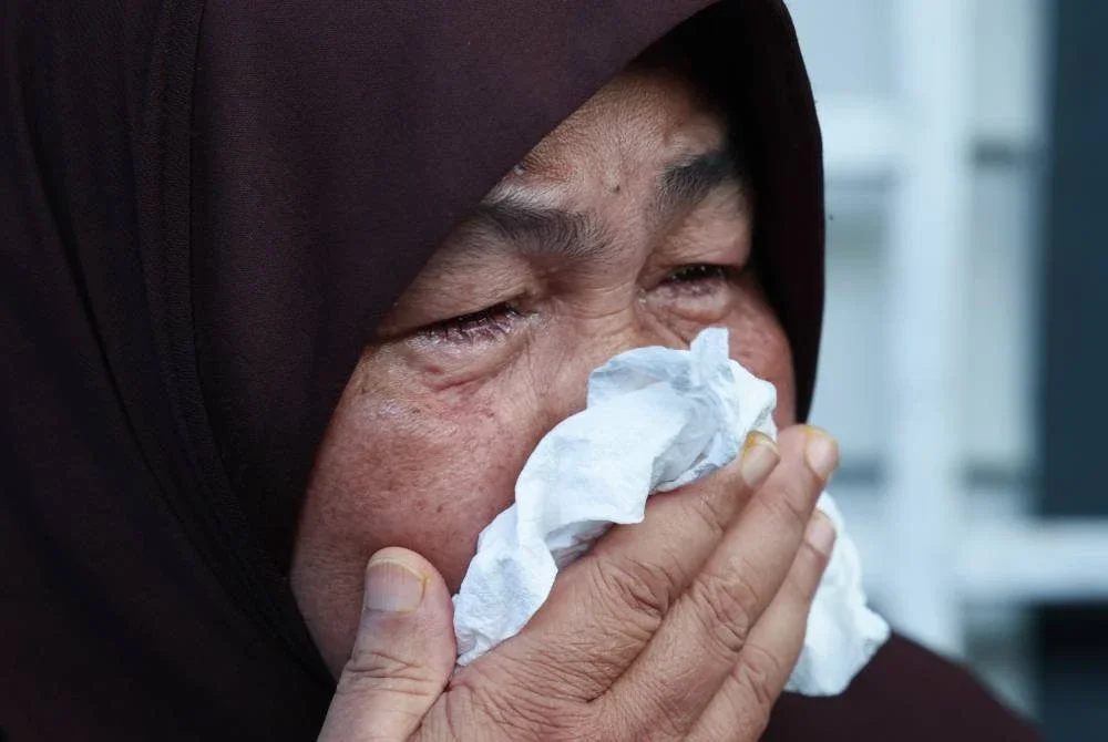 Maznah Ismail, 64, kelihatan sebak semasa menceritakan mengenai anak lelakinya Allahyarham Koperal Mohd Hafizul Izham Mazlan, yang dirempuh kenderaan dinaiki penjenayah yang sedang melakukan jenayah pecah rumah di Taman Golf, Alor Setar, petang semalam, semasa ditemui di Kampung Pak Kancil pada Jumaat. Foto Bernama